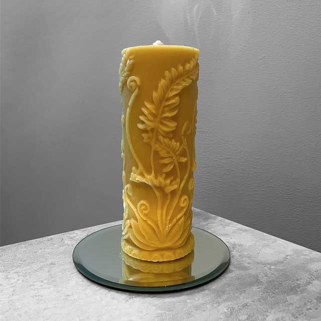 A pillar candle embossed with a fern design.